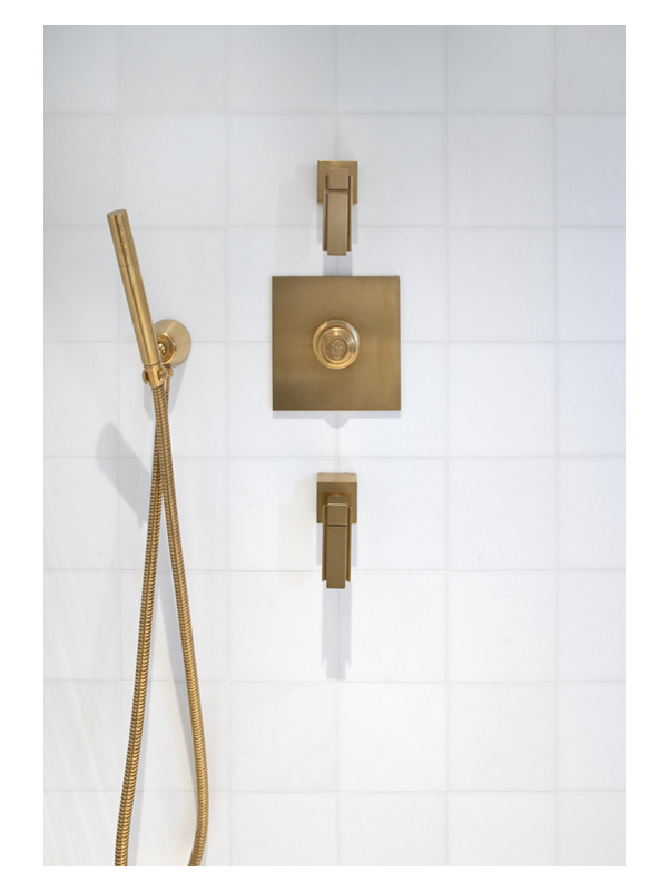 White Thassos marble shower wall with brass fixtures